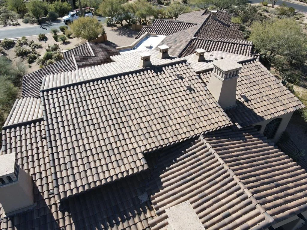 Aerial view of Spanish tile roof with clay barrel tiles, metal flashing, and chimney caps on multi-section home