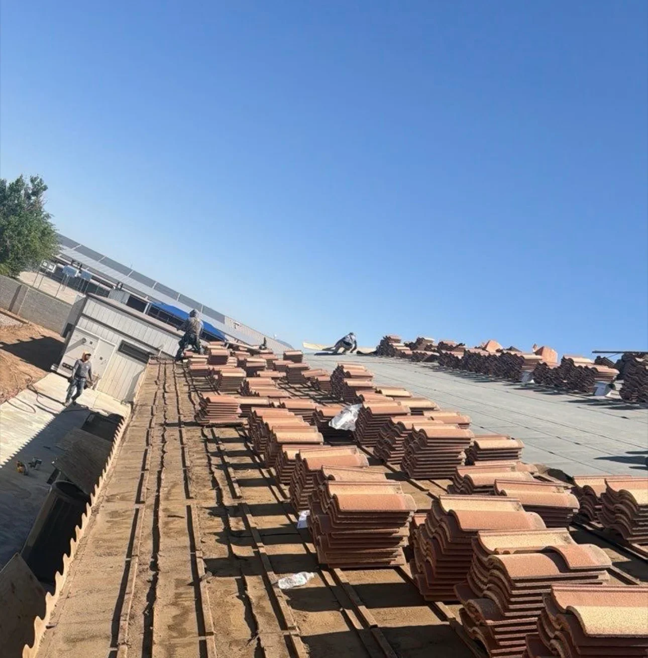 Rows of terracotta clay barrel tiles organized on staging area with metal supports and storage structures